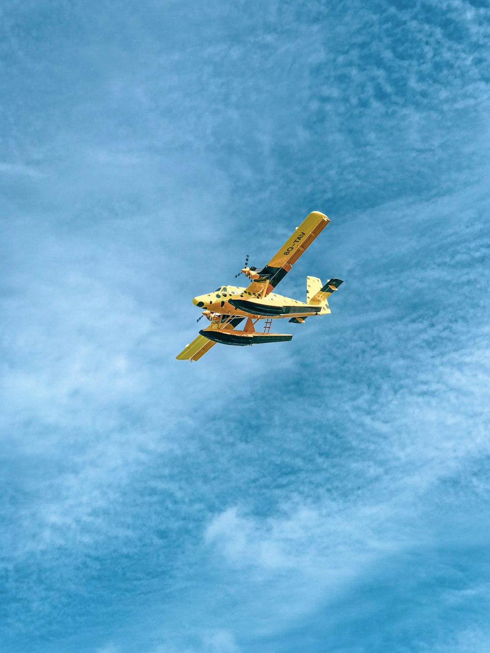 a small plane flying through a cloudy blue sky