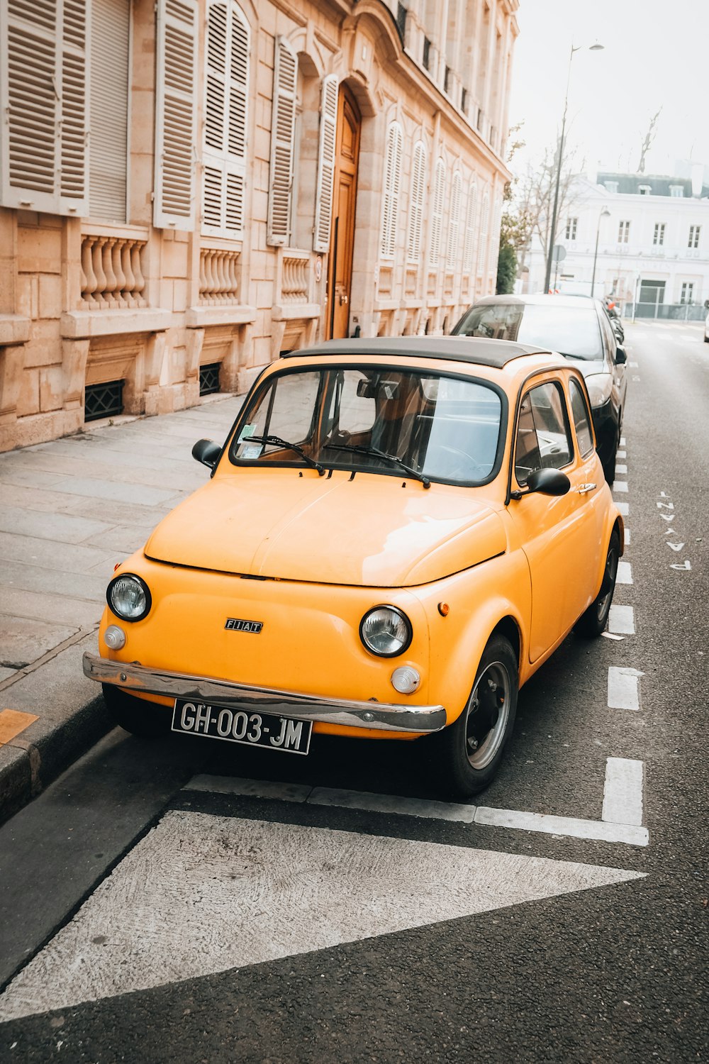 a small yellow car parked on the side of the road