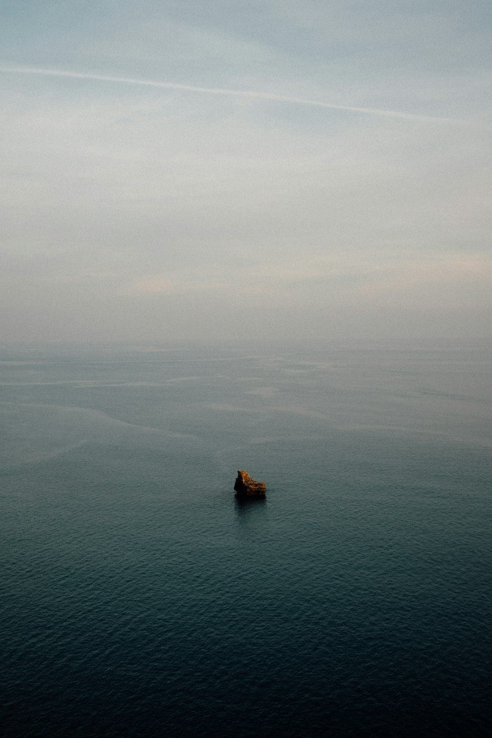 a lone boat floating in the middle of the ocean