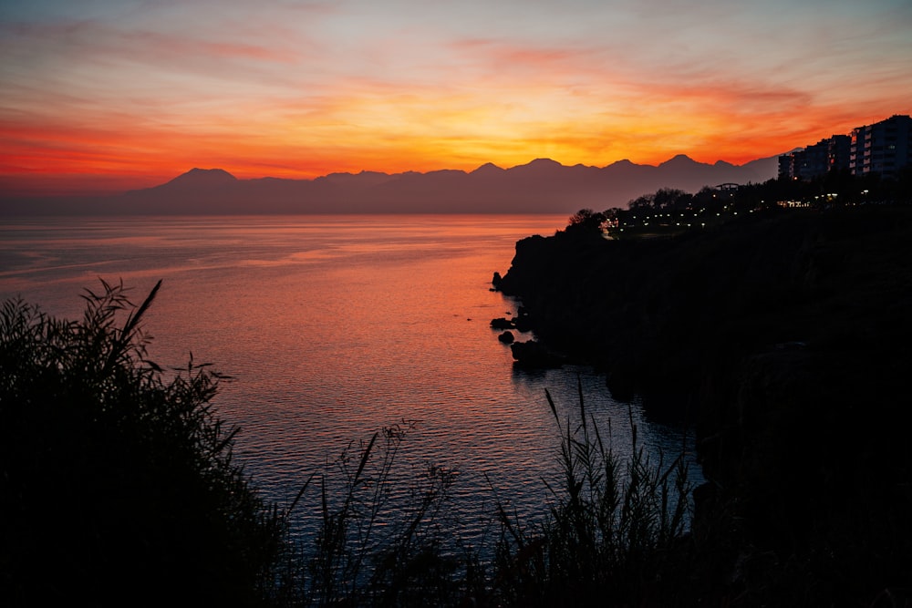 a sunset over a body of water with mountains in the background