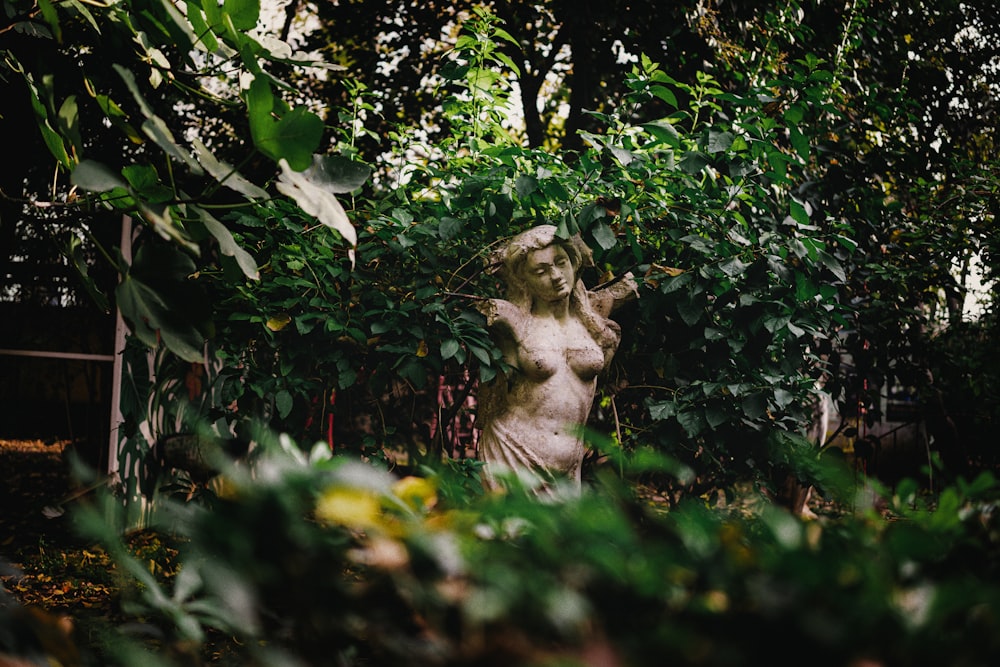 a statue of a woman surrounded by greenery