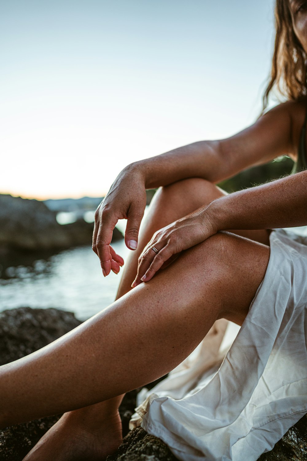 a woman is sitting on a rock by the water