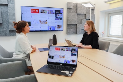 two women sitting at a table with laptops