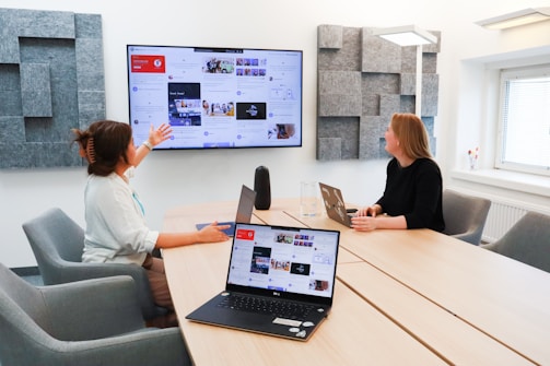 two women sitting at a table with a laptop