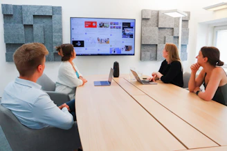 Team discussing advanced financial models and projections on a large screen in a modern office.