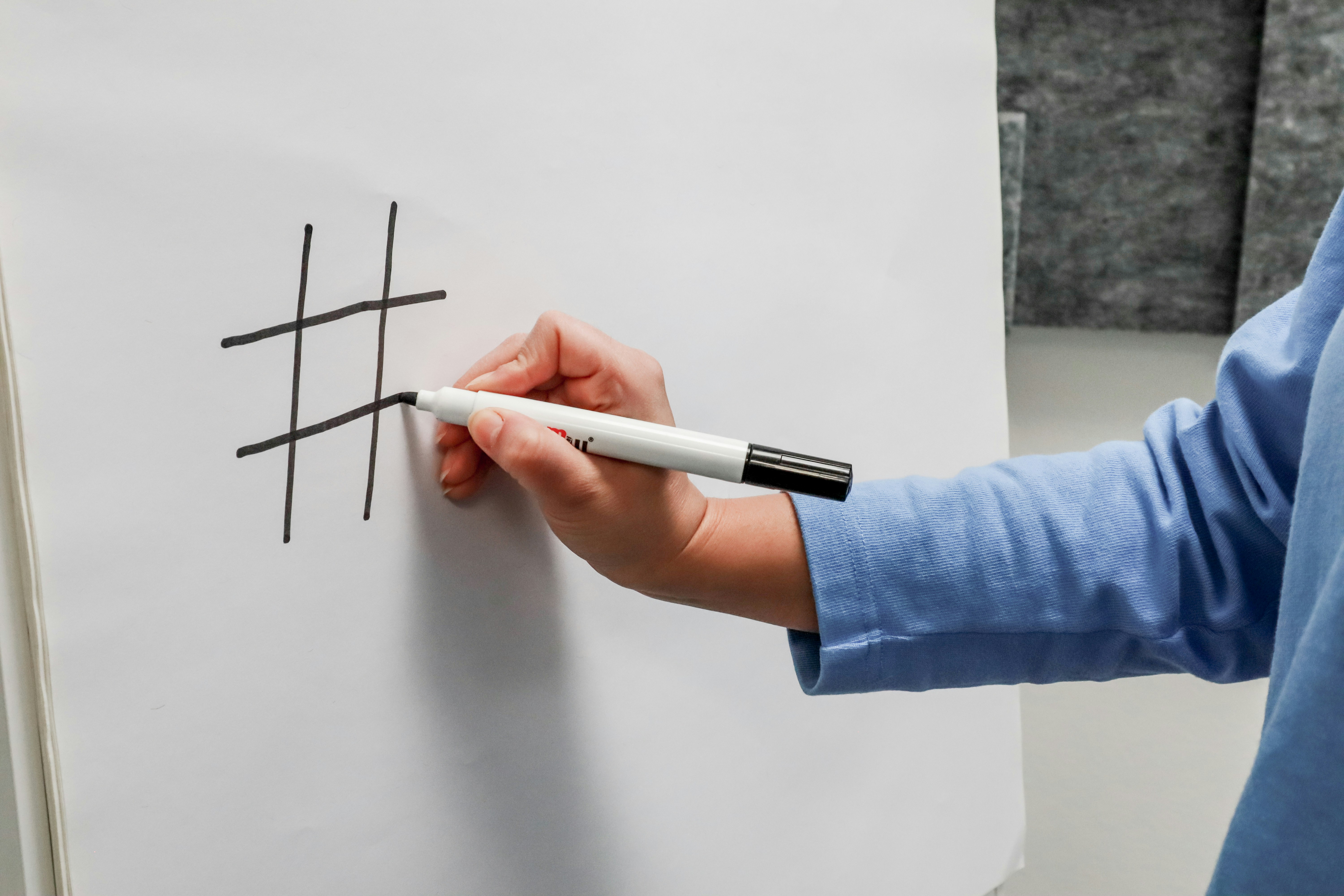 Person drawing a hashtag on a white board
