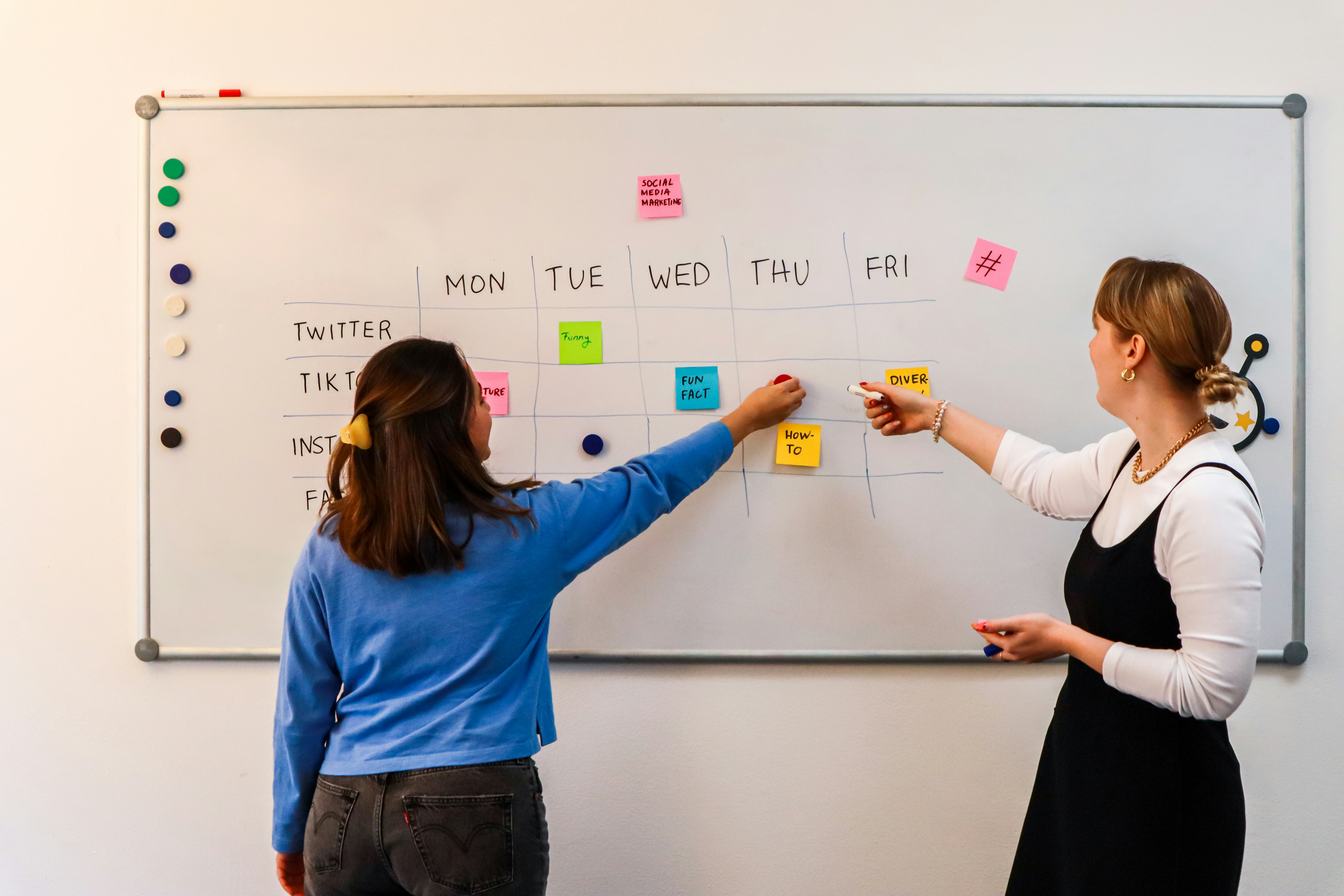 Marketing team planning weekly content for social media in front of a white board