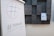 A flip chart displays a simple grid drawing within a red speech bubble and the word '#TEAMWORK' is written below with a green underline. In the background, a textured wall with a modular design holds a small paper labeled 'WALLS.IO'.