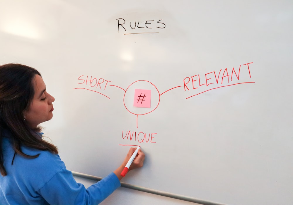 a woman writing on a whiteboard with a marker