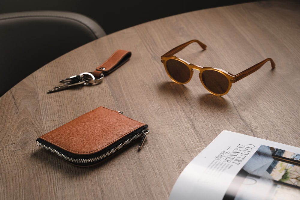 a wooden table topped with a wallet and sunglasses