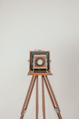 A vintage tintype camera set up on a wooden tripod with soft natural light highlighting its intricate details.