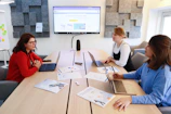 Group of women leaders sharing ideas around a modern conference table in a bright room.