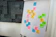 A flip chart with various colored sticky notes attached, containing words and concepts like 'people 1st', 'respect', 'diversity', 'vision', and 'teamwork'. The notes are predominantly pink, yellow, green, and blue. The background features a wall with geometric, dark gray panels.