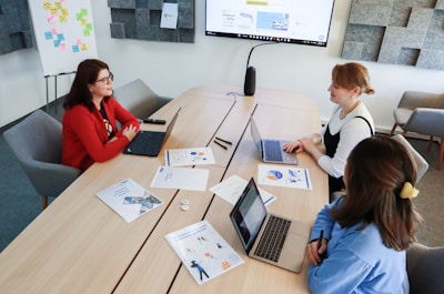 a group of people sitting around a table with laptops