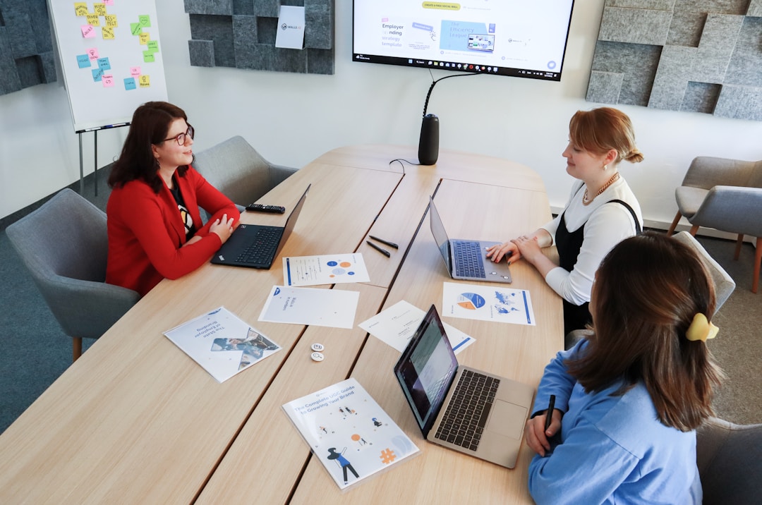 Team members engaged in discussion and collaboration in an office work environment, with a whiteboard behind them displaying notes and ideas