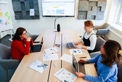 a group of women sitting around a table working on laptops
