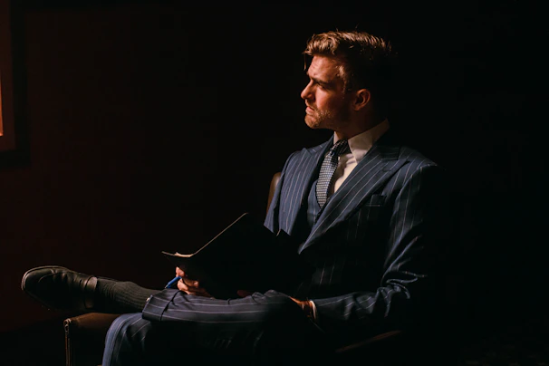 Elegant businessman in coffee-colored suit reviewing paperwork under warm, soft office lighting
