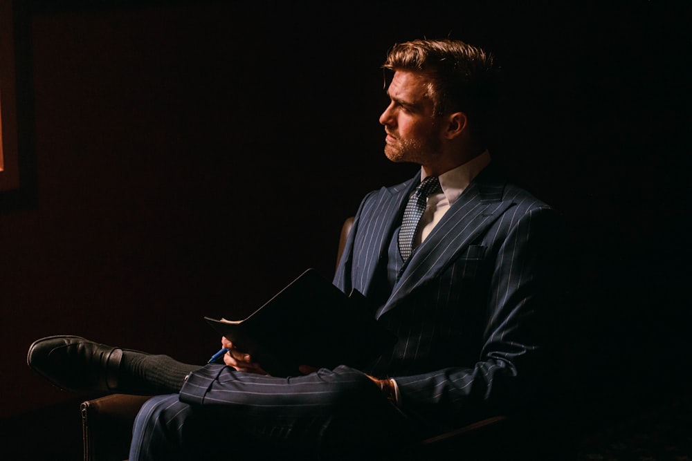 a man in a suit sitting in a dark room