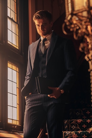 a man in a suit standing in front of a window