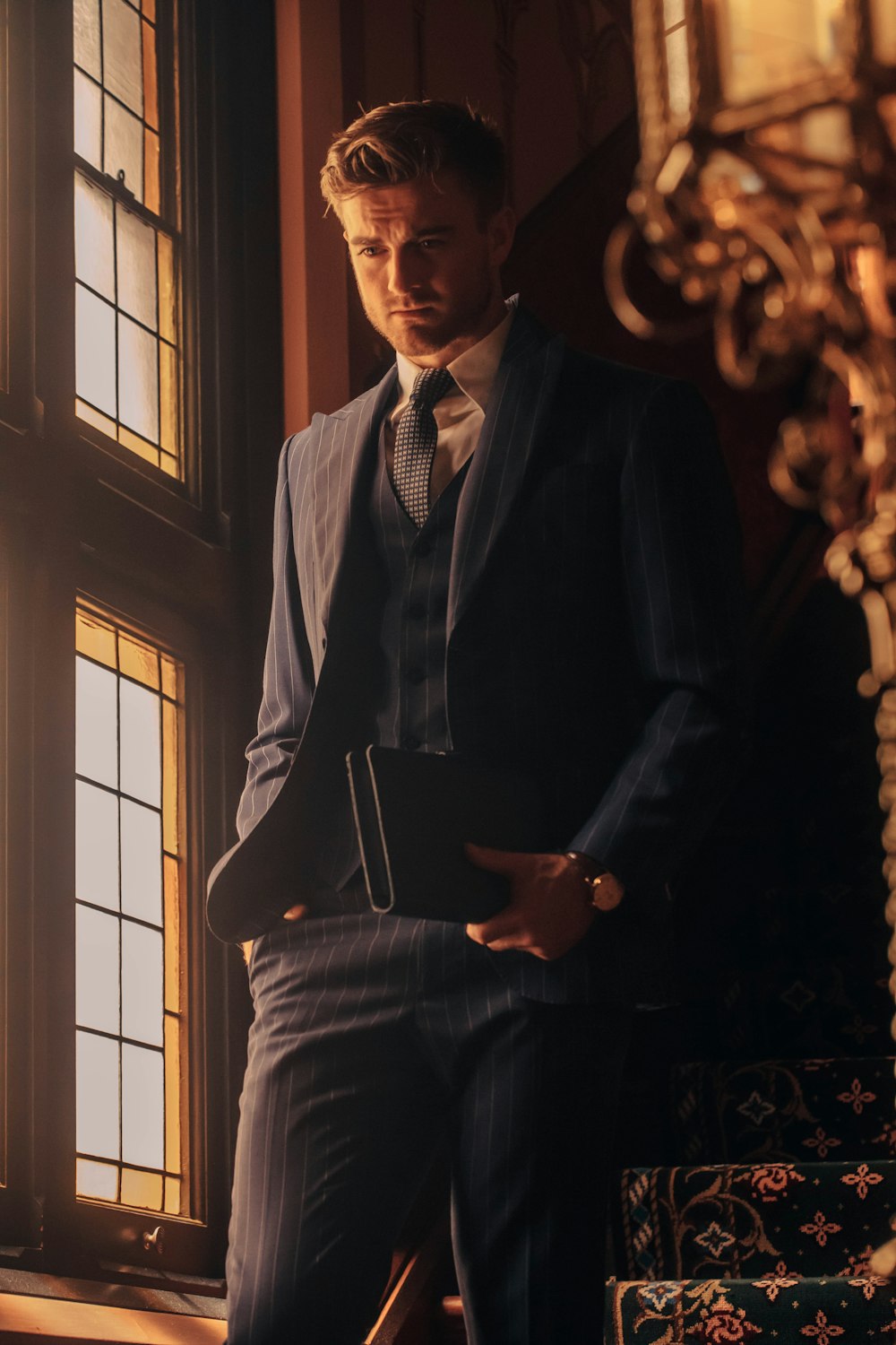 a man in a suit standing in front of a window