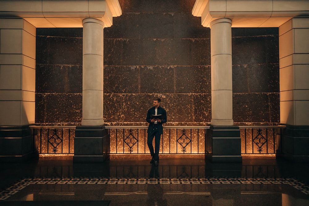 a man in a suit standing in front of a wall