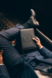 a man in a suit is holding a laptop