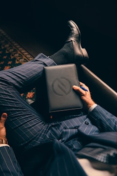 a man in a suit is holding a laptop