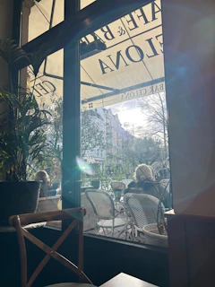 Sunlight streaming through large windows onto a bustling coffee shop patio.