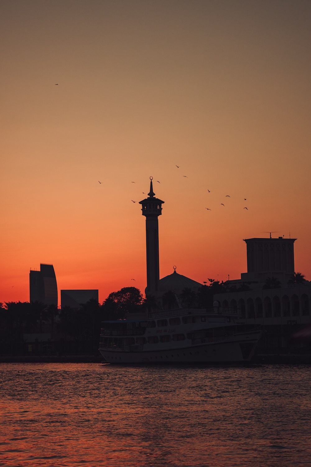 the sun is setting over the water with a boat in the foreground