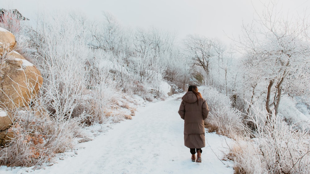 a woman walking down a snow covered path