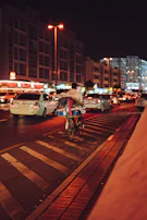 An urban commuter riding an e-bike through a city street at dusk, city lights glowing.