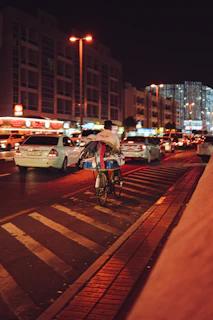 An urban commuter riding an e-bike through a city street at dusk, city lights glowing.