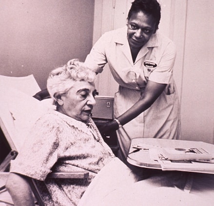 a woman in a hospital bed being assisted by a nurse