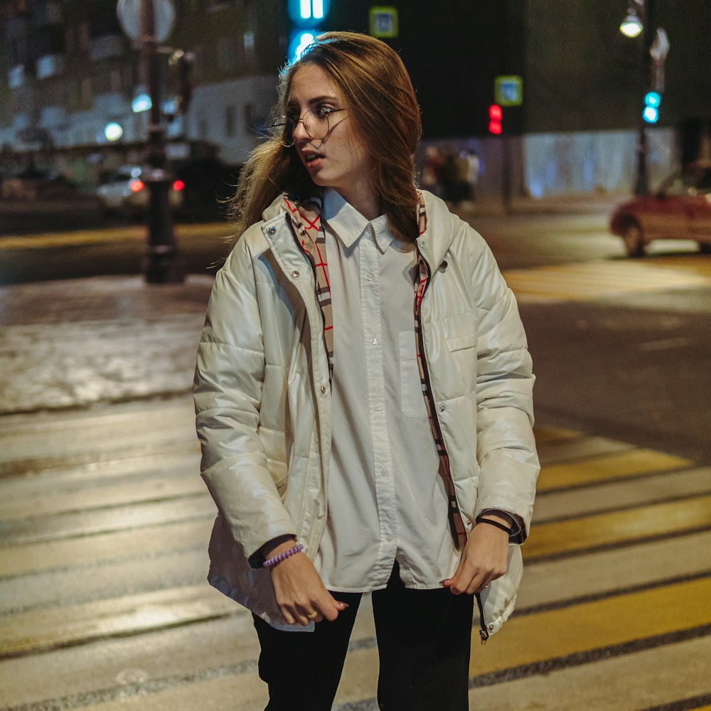 a woman standing on the side of a road at night