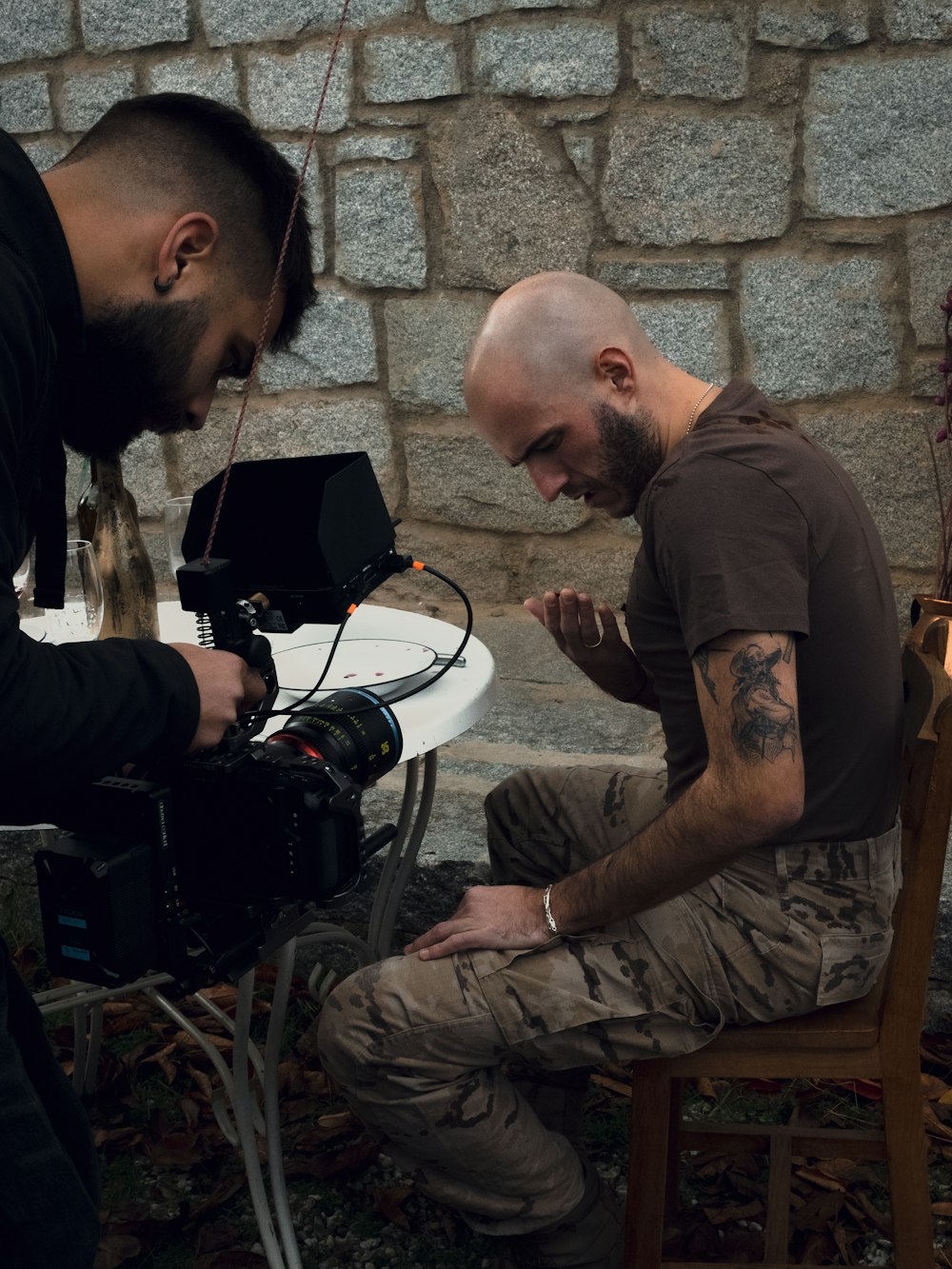 a man sitting on a chair next to a man with a camera