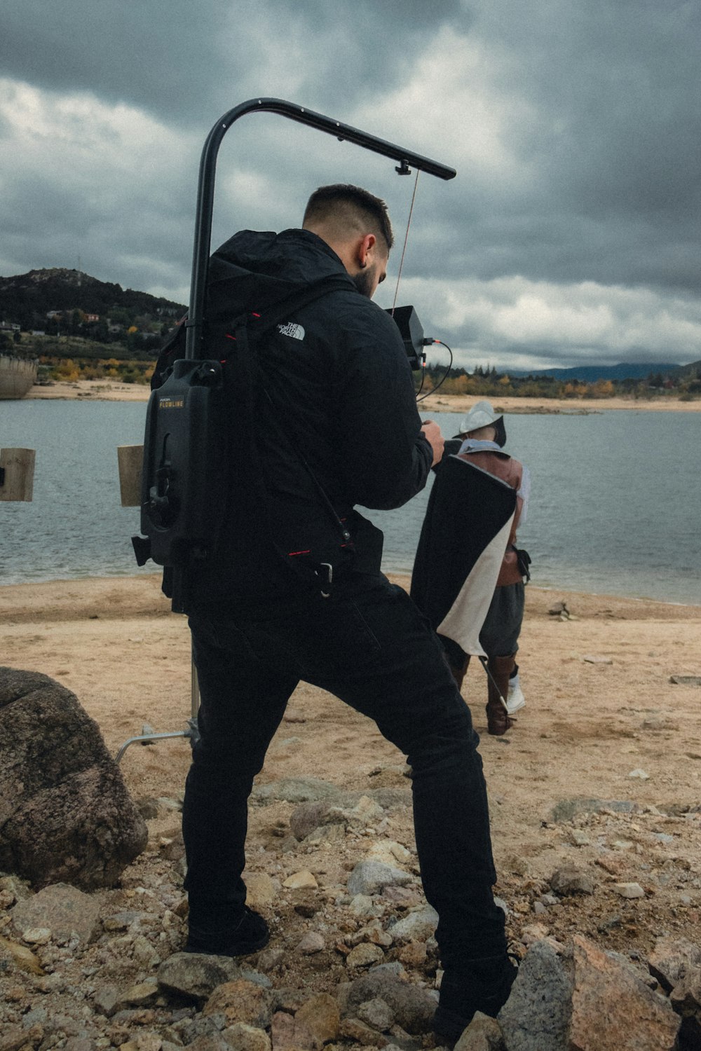 Ein Mann steht an einem felsigen Strand und hält eine Kamera in der Hand