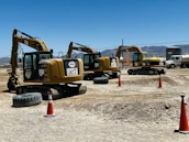 Dump trucks lined up ready for aggregate hauling on a sunny day at a construction site.