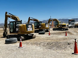 Dump trucks lined up ready for aggregate hauling on a sunny day at a construction site.