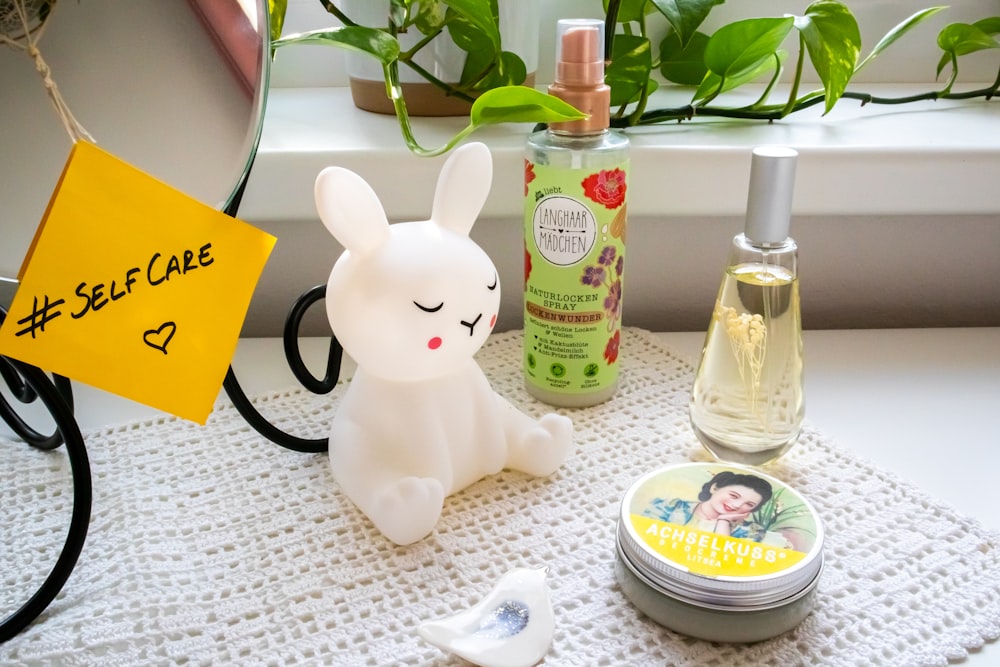 a white rabbit figurine sitting on top of a table next to a bottle