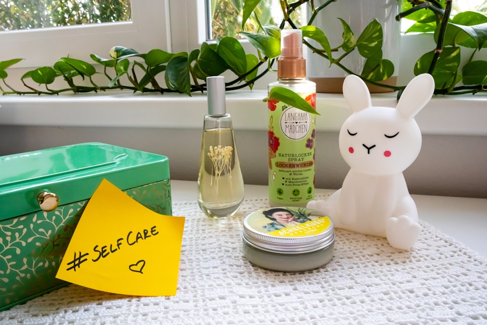 a table topped with a container of lotion and a bunny figurine