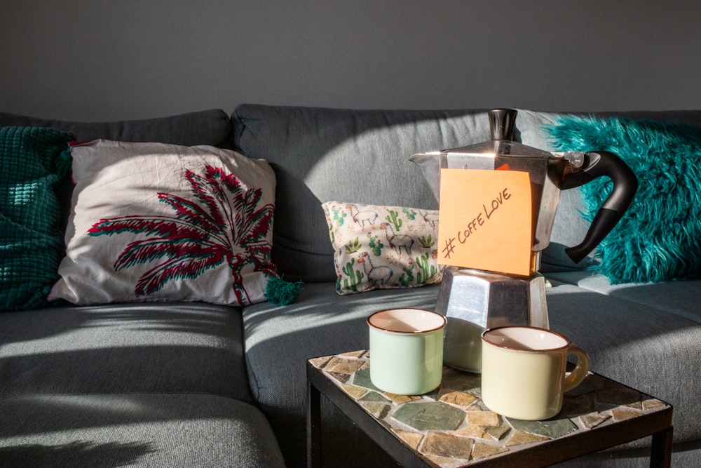 two cups of coffee sit on a table in front of a couch