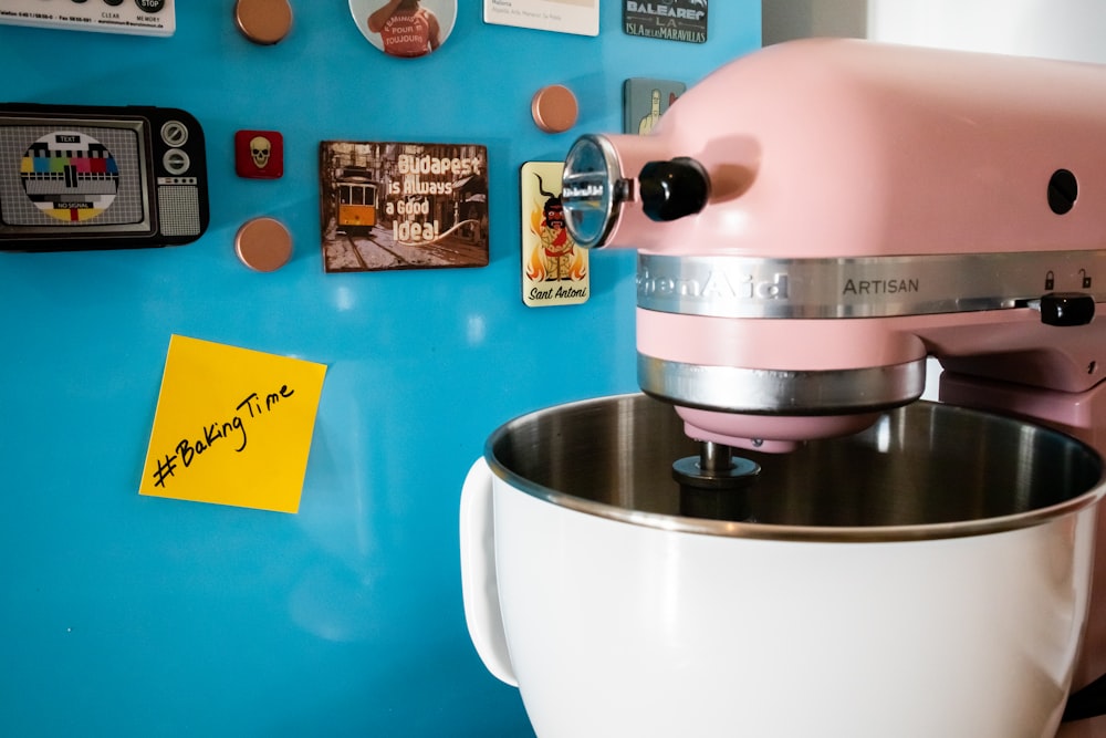 a pink mixer sitting in front of a blue wall