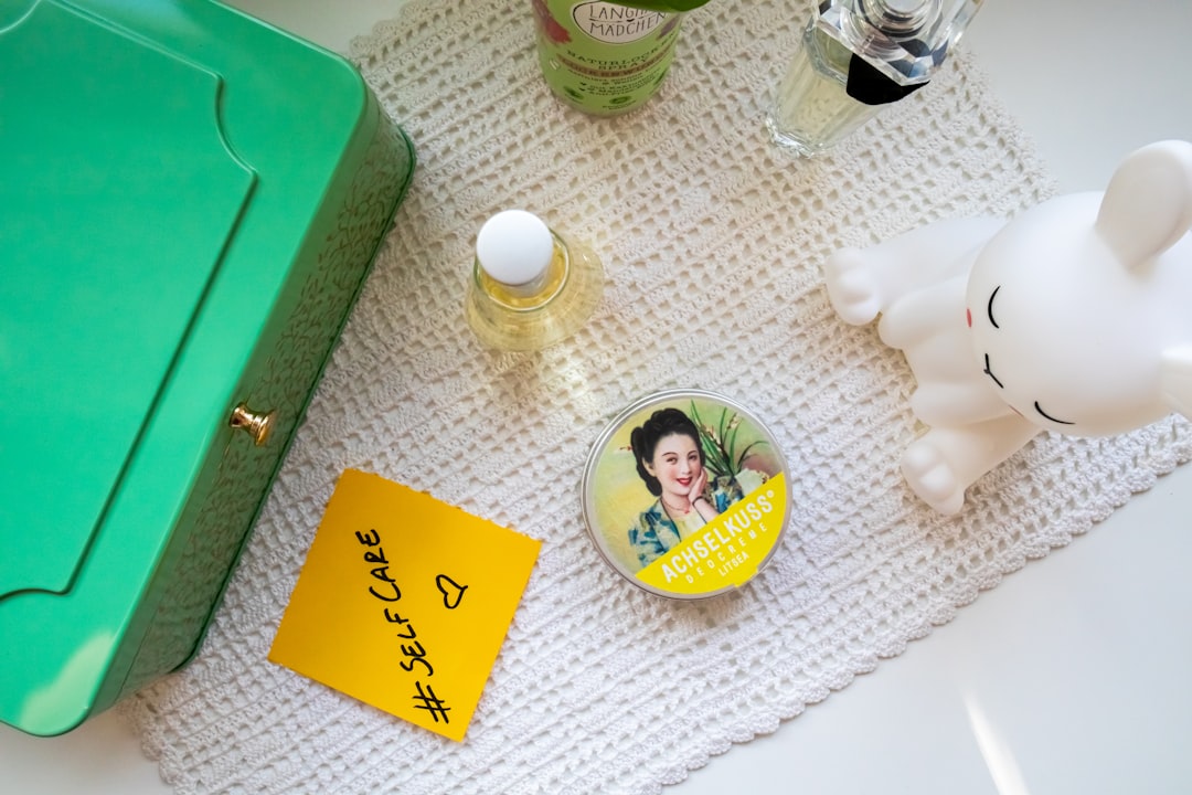 a green box with a picture of a woman on it, Dresser with cosmetic products and a sticky note with the hashtag #selfcare on it