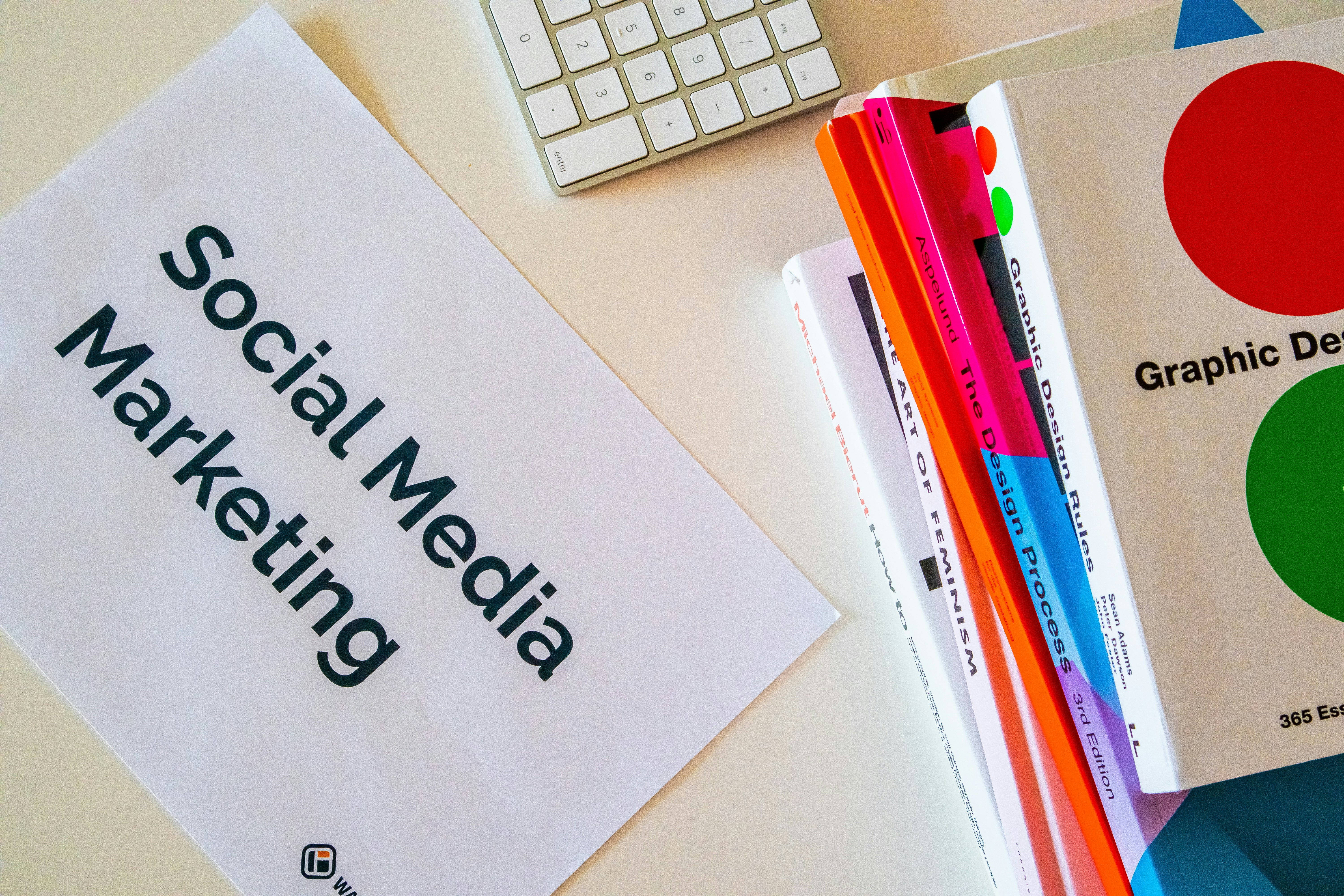 Home desk with design books and a paper with the words Social Media Marketing on it