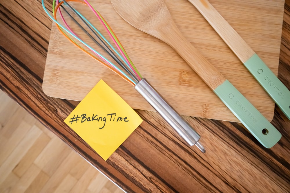 a wooden cutting board topped with a whisk and a whisk