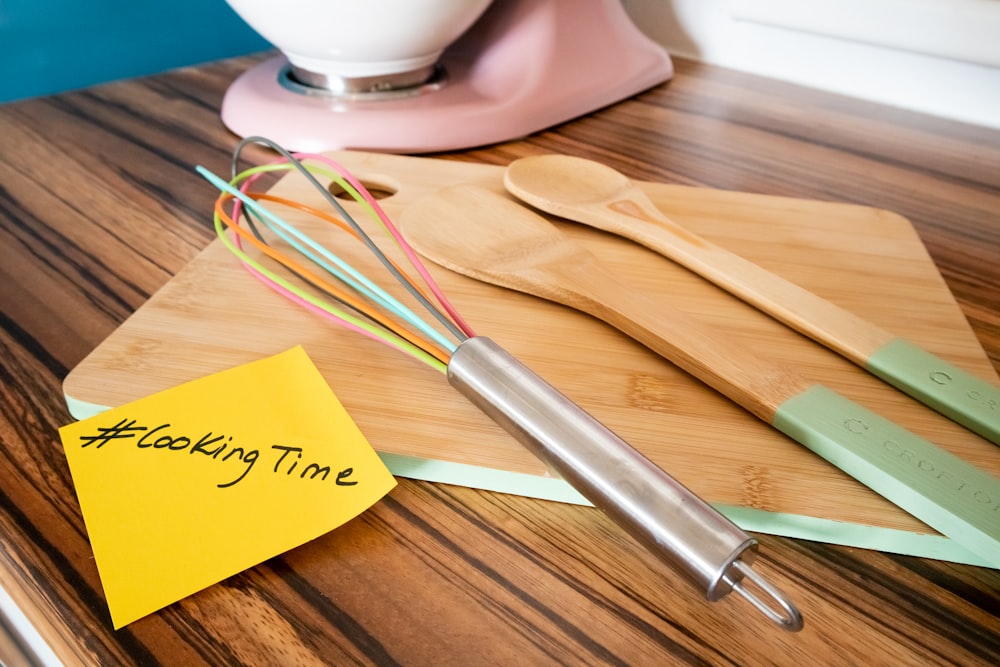 a wooden table topped with kitchen utensils and a note