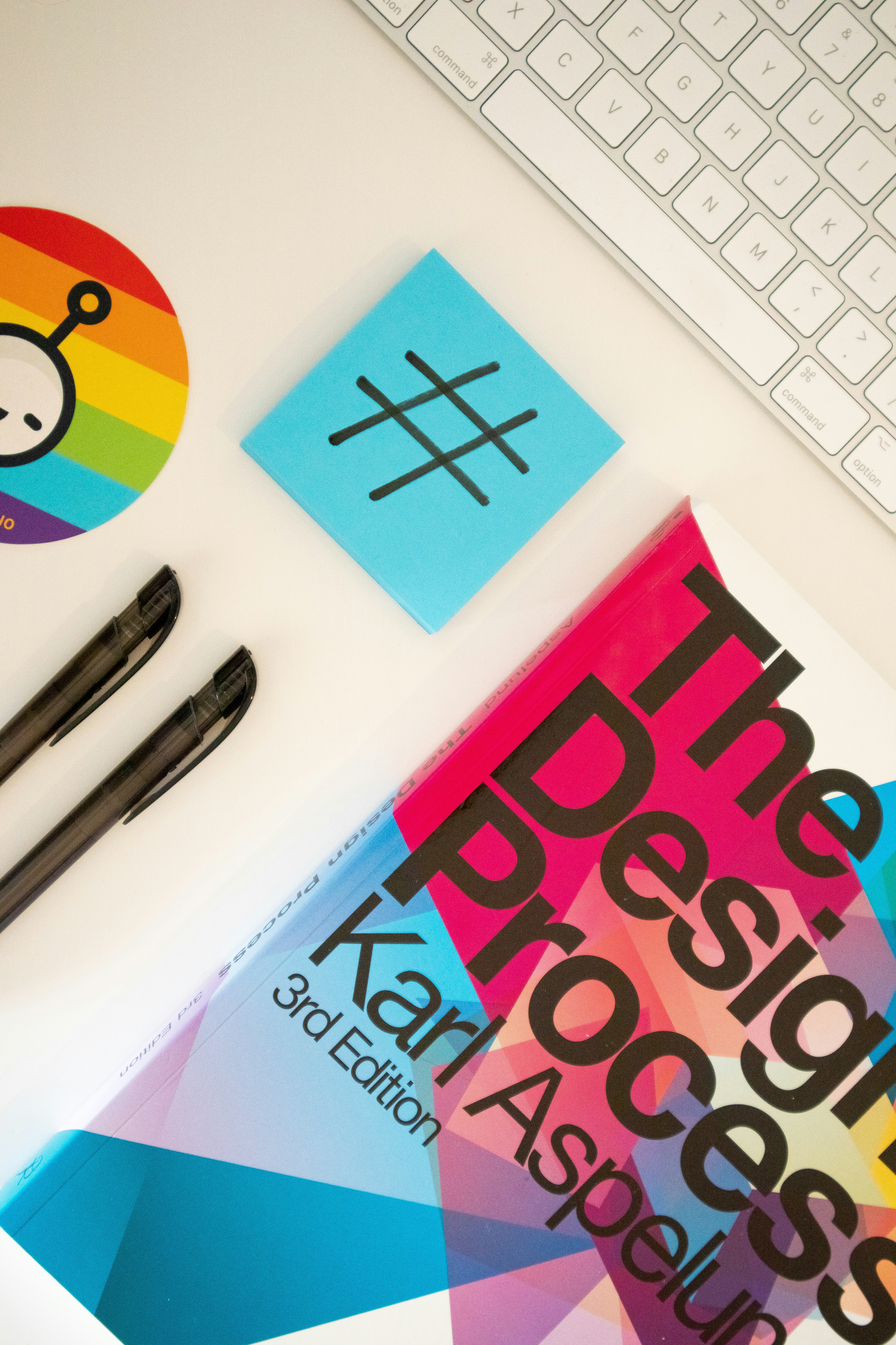 Home desk with a design book, stationary elements and a sticky note with a hashtag on itby Walls.io