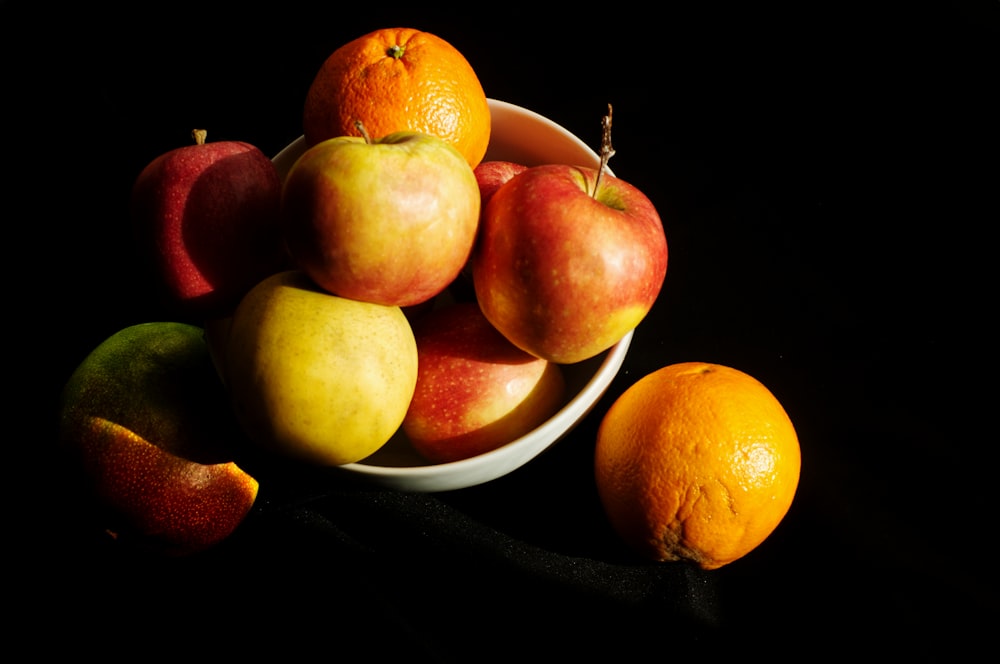 a white bowl filled with apples and oranges