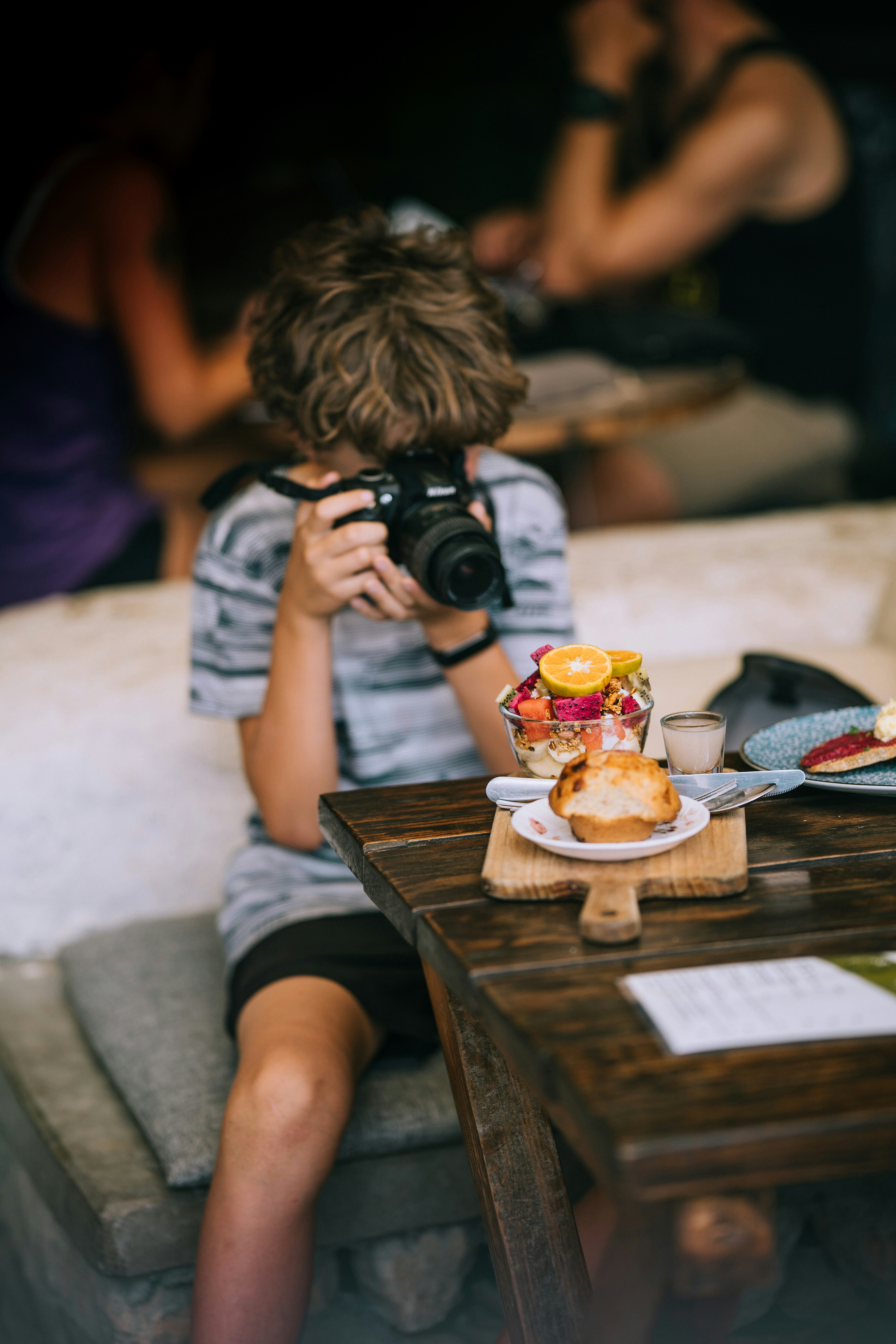 Un garçon prend une photo de nourriture sur une table