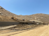 Operators working with earthmoving machines clearing and preparing land in a construction site.
